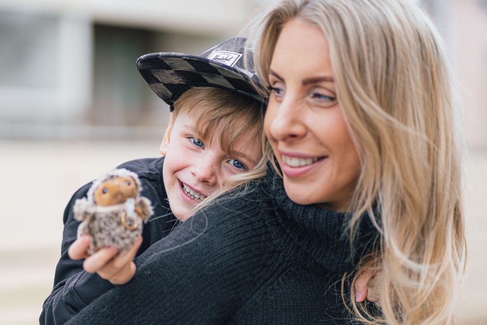 Two people share a joyful moment while holding a small hamster together outdoors.