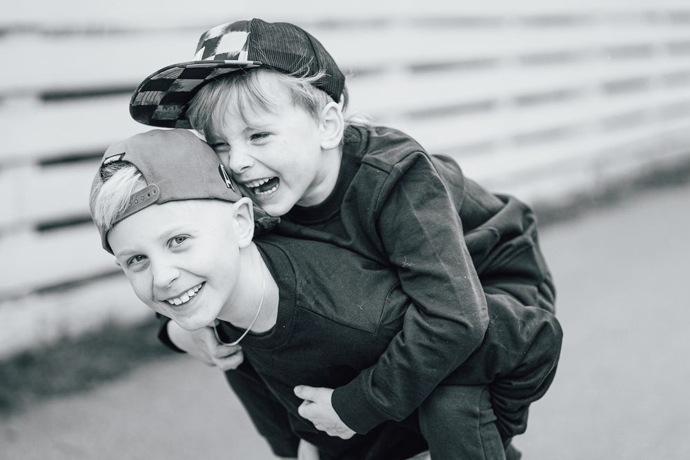 Black and white photo showing joyful outdoor piggyback ride between two people in winter clothing.