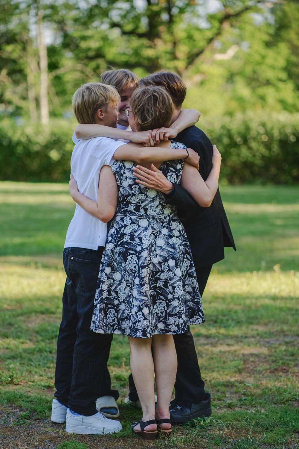 Group of people sharing an emotional embrace outdoors in a garden setting.