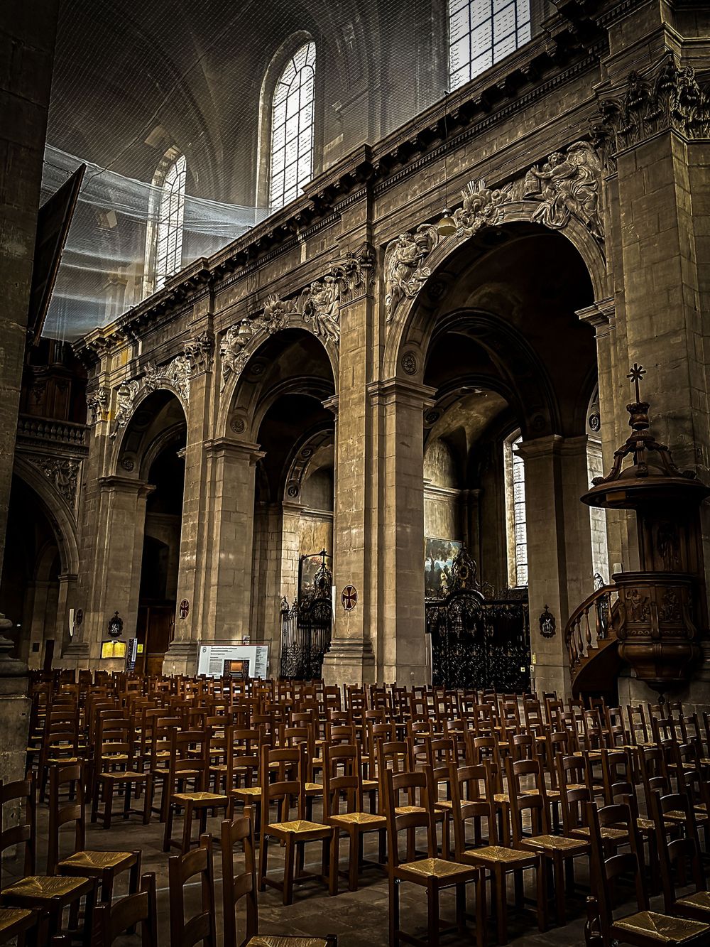Gothic church interior with rows of wooden chairs and ornate stone arches.