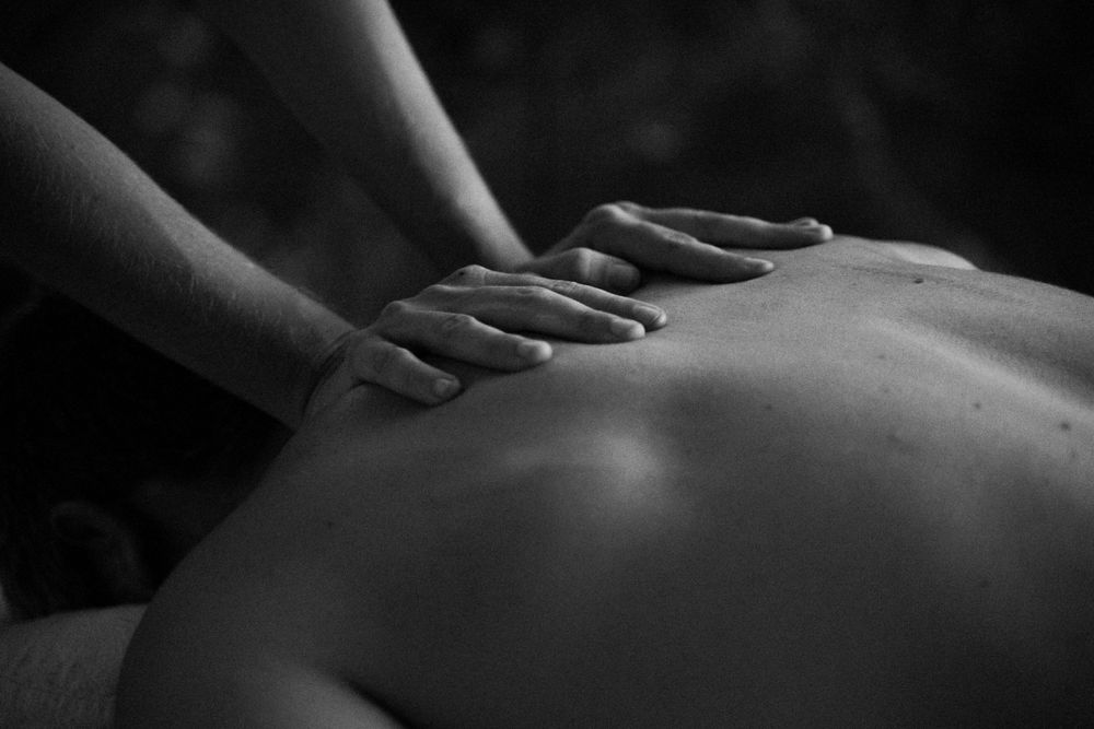 Dark artistic photograph showing massage therapy techniques in monochrome.