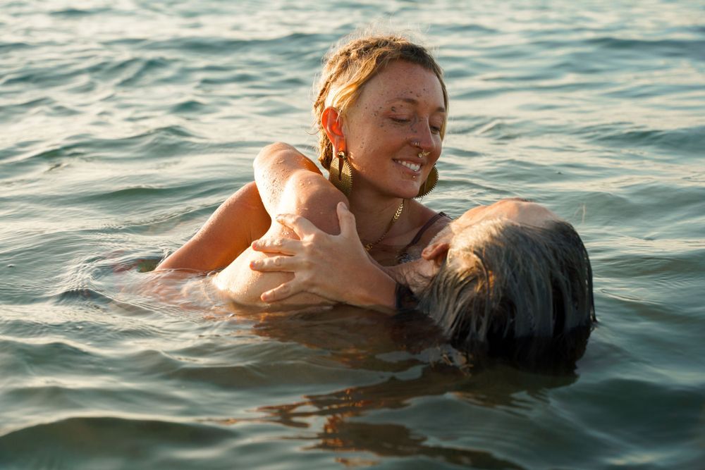 Two people floating together in calm ocean waters during golden hour.
