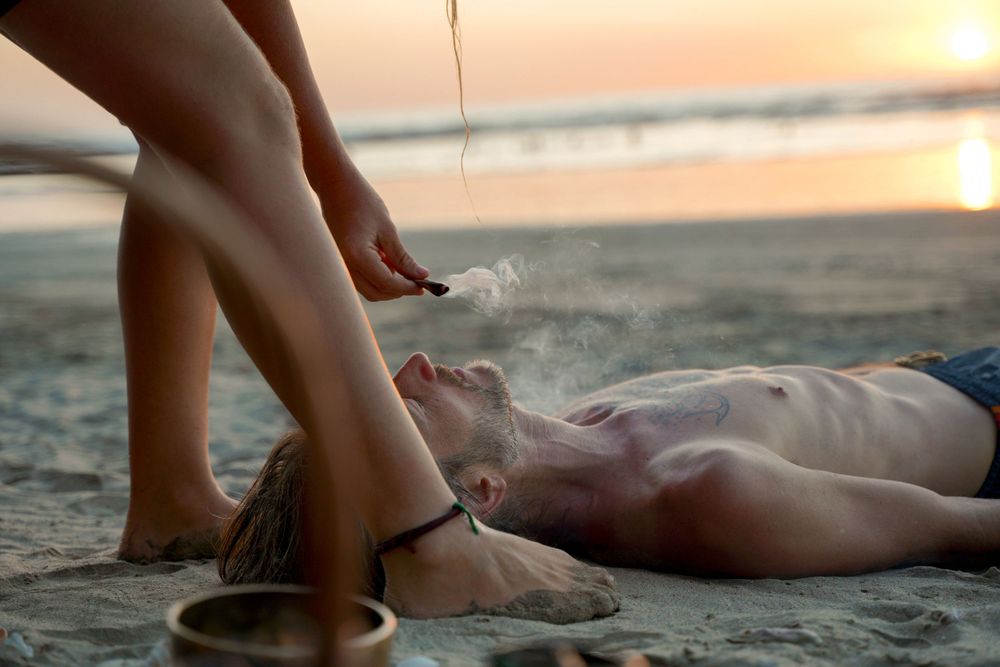 Sand and water therapy treatment being performed on a beach at sunset.