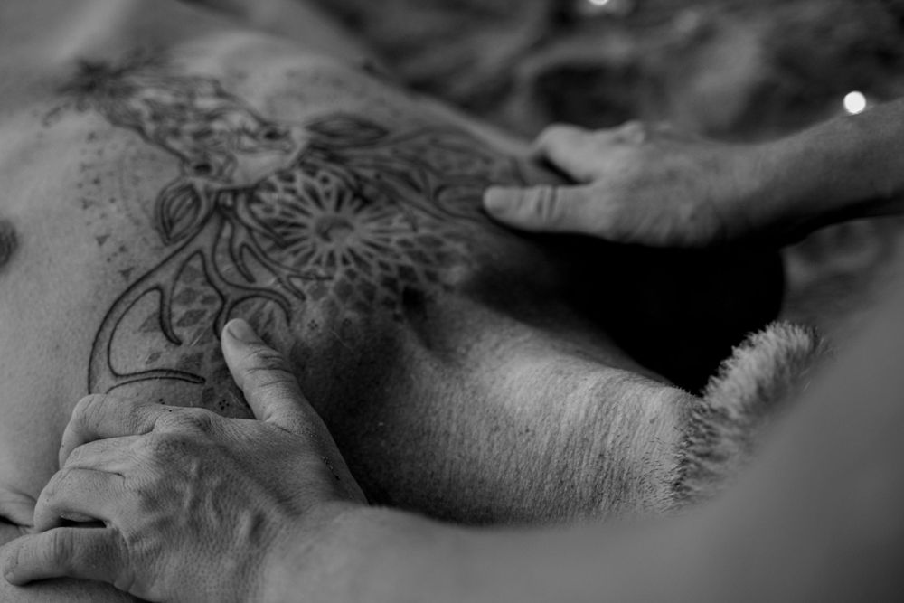 Monochrome detail of massage treatment near decorative tattoo artwork.