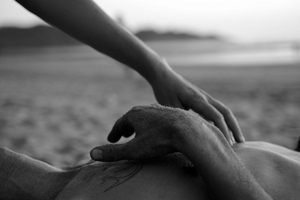 Close-up black and white shot of hands performing healing bodywork massage.