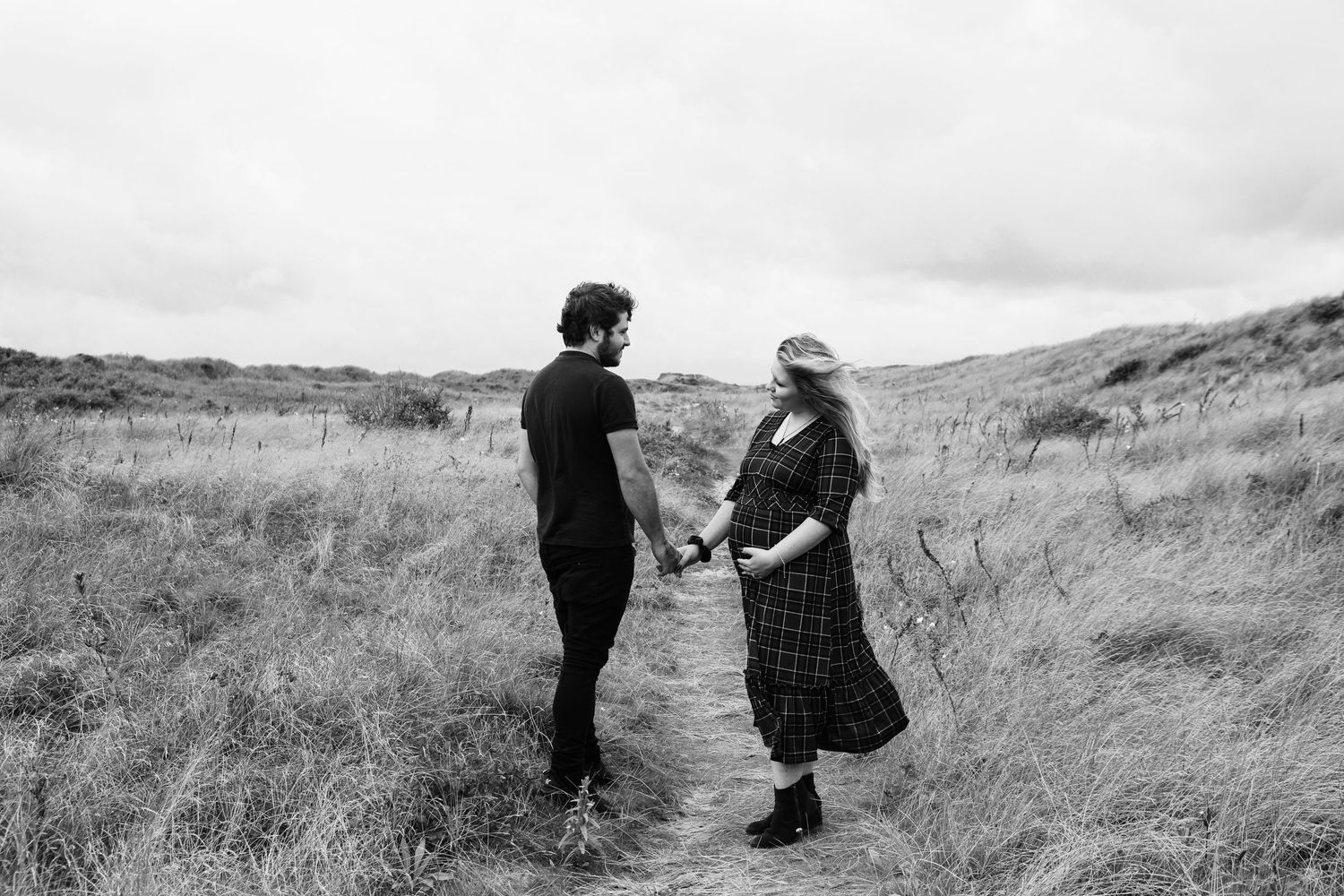 Black and white photo of two people having a conversation in a grassy field.