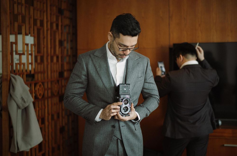Business people in professional attire standing in a hallway reviewing messages on mobile devices.