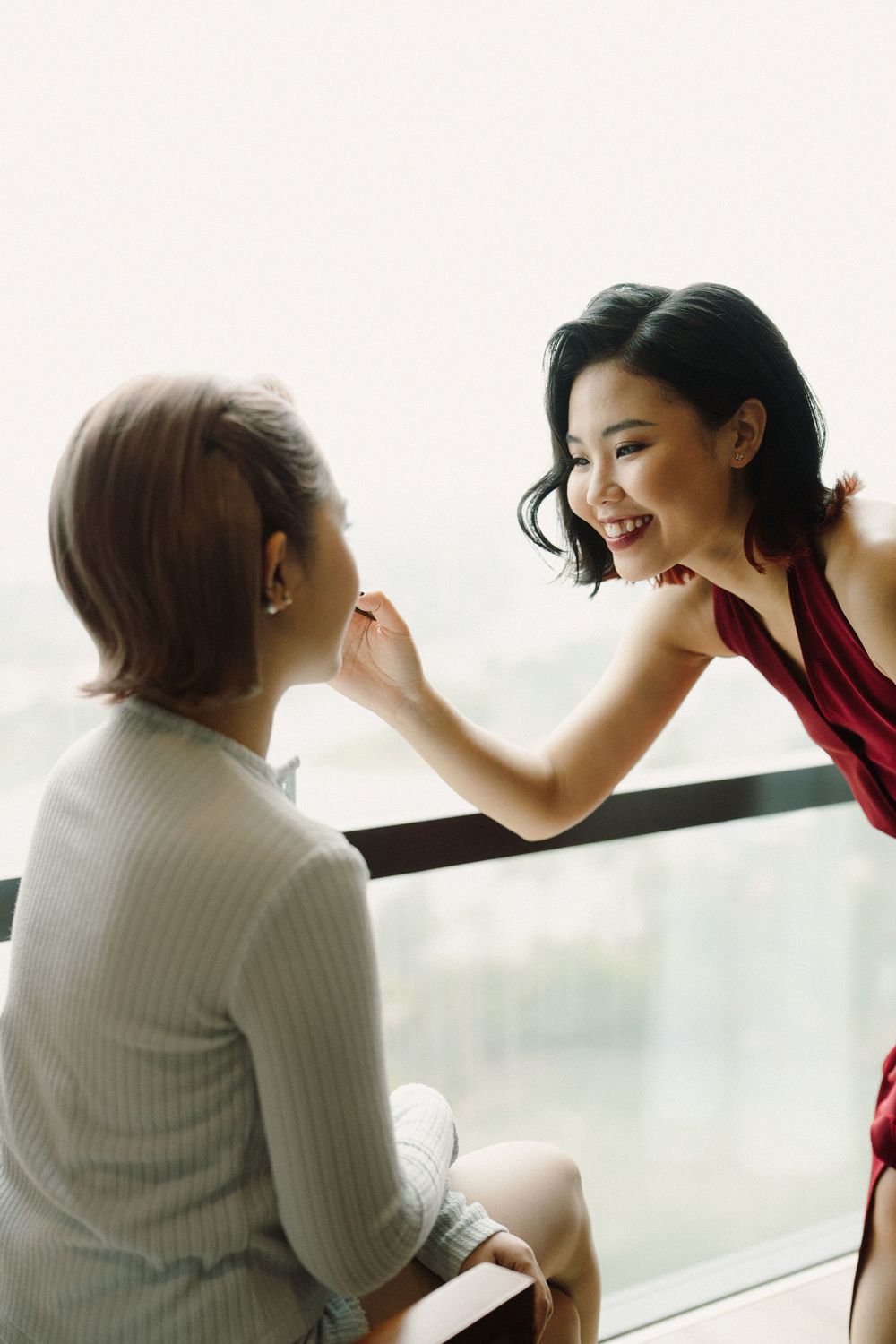 Series of joyful candid moments shared between a bride and groom by a window in natural light.