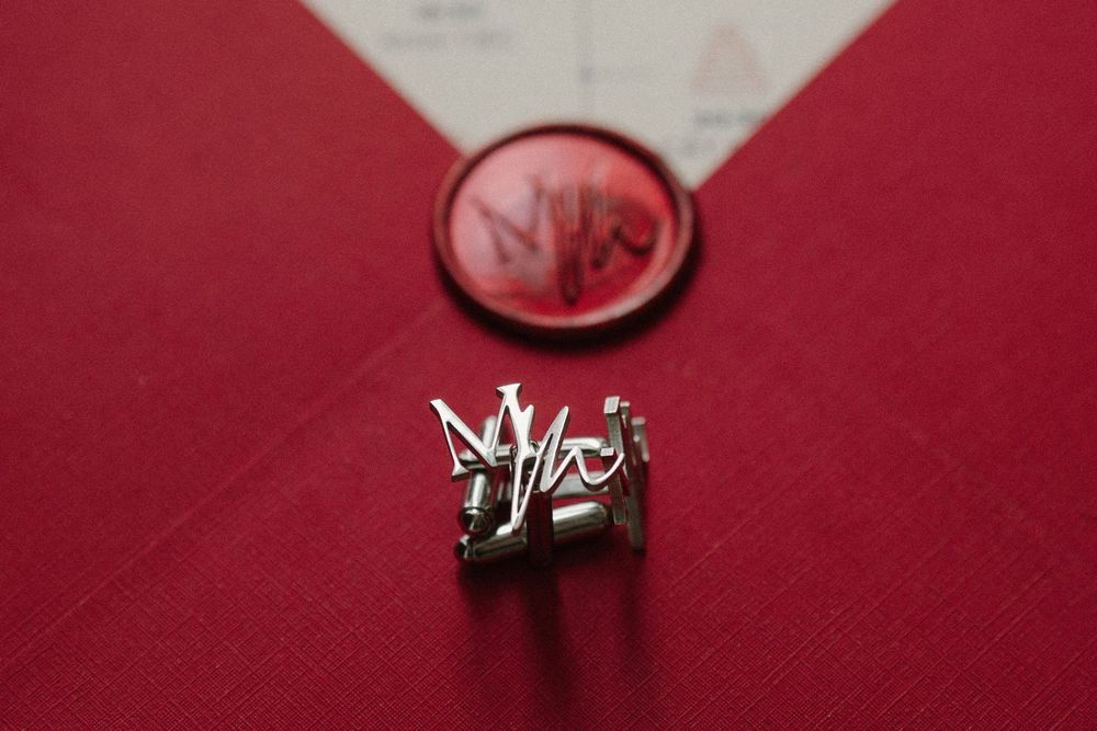 An elegant silver ring and red wax seal displayed on a red cloth background.