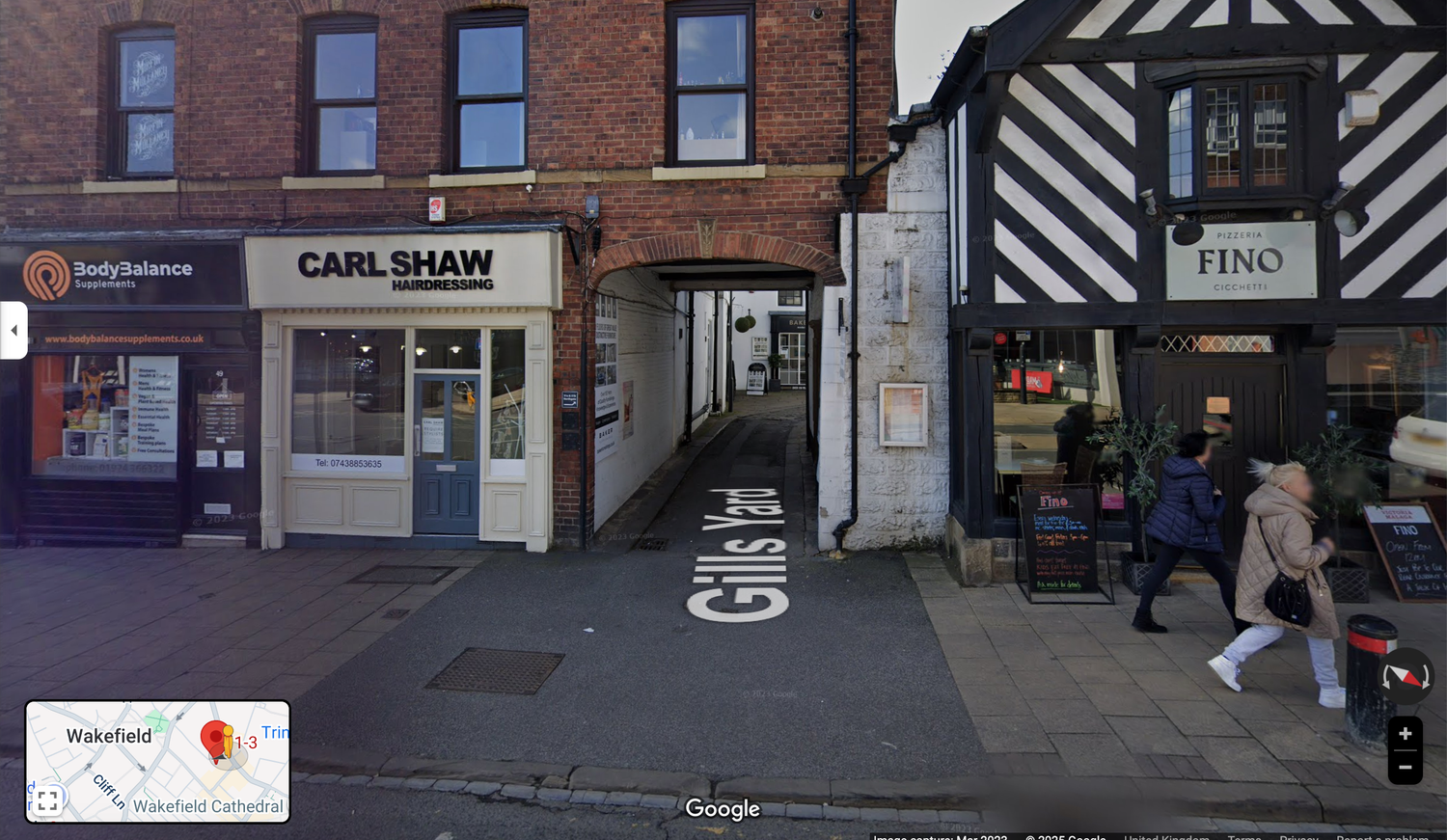 Commercial street view showing connected brick buildings with various storefronts and businesses.
