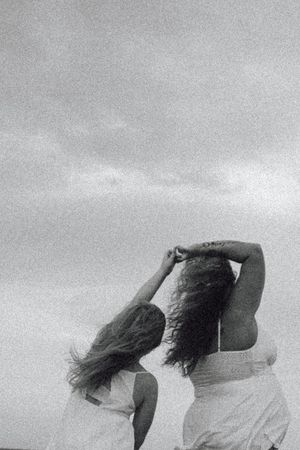 Black and white artistic sequence showing figures with hair flowing in the wind creating dynamic motion against sky.