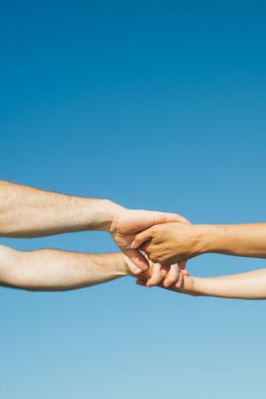 Two hands reaching towards each other against a bright blue sky background in a series of connected images.