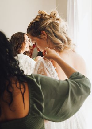 A tender moment between two figures sharing affection while wearing white and green colored clothing in soft lighting.