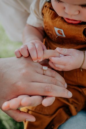 A closeup sequence of small hands examining a silver ring with precise and careful movements against a brown fabric background.