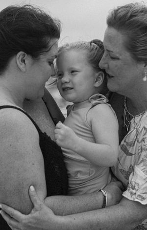 Intimate black and white portrait of three people in close embrace showing tender family moment.