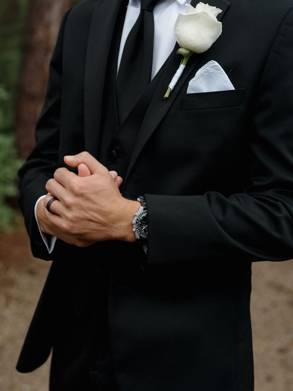 Close-up detail of black tuxedo with white boutonniere on the lapel.
