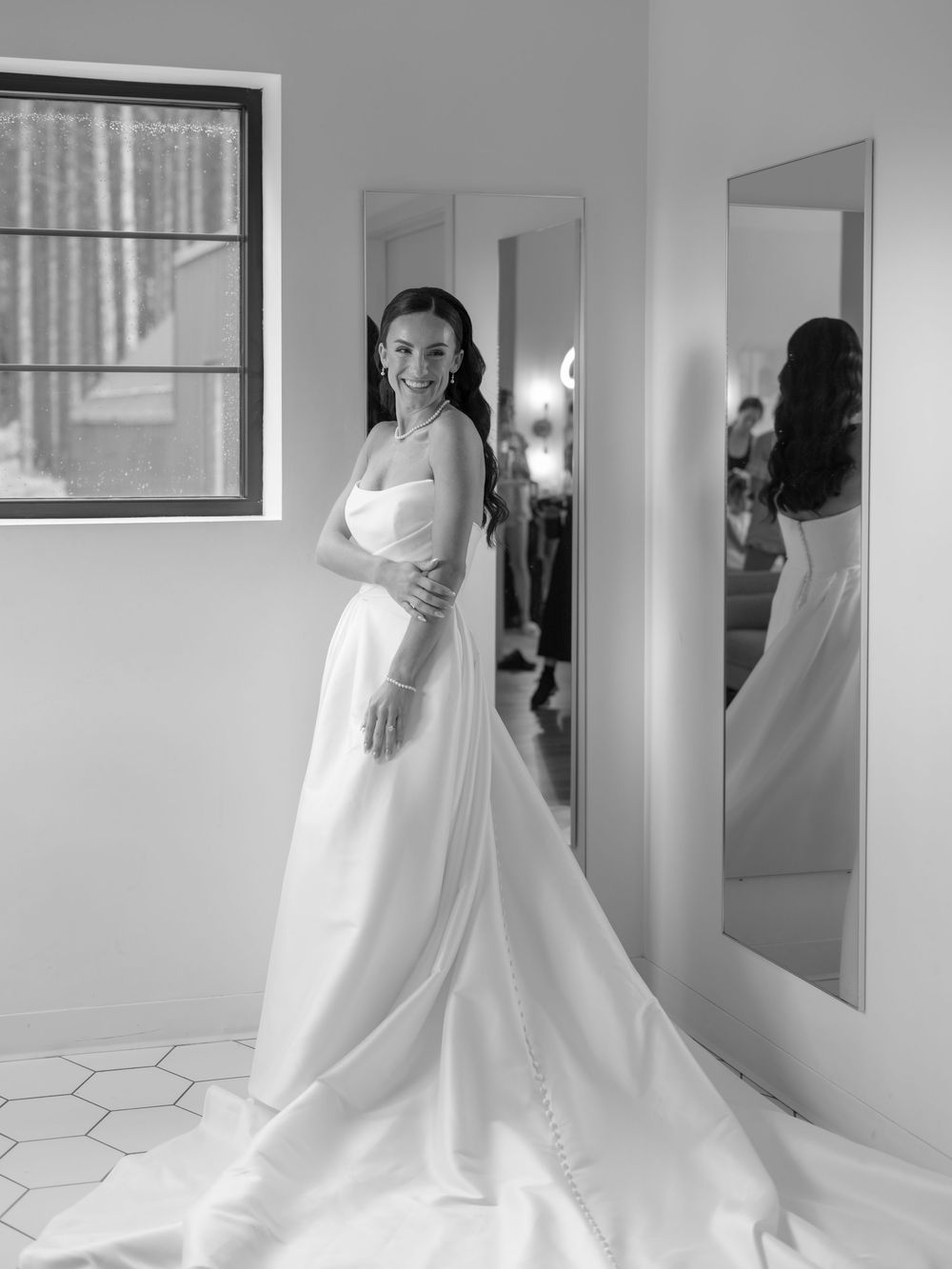 Sequence showing a bride in an elegant white wedding dress getting ready in front of mirrors in a bright room.