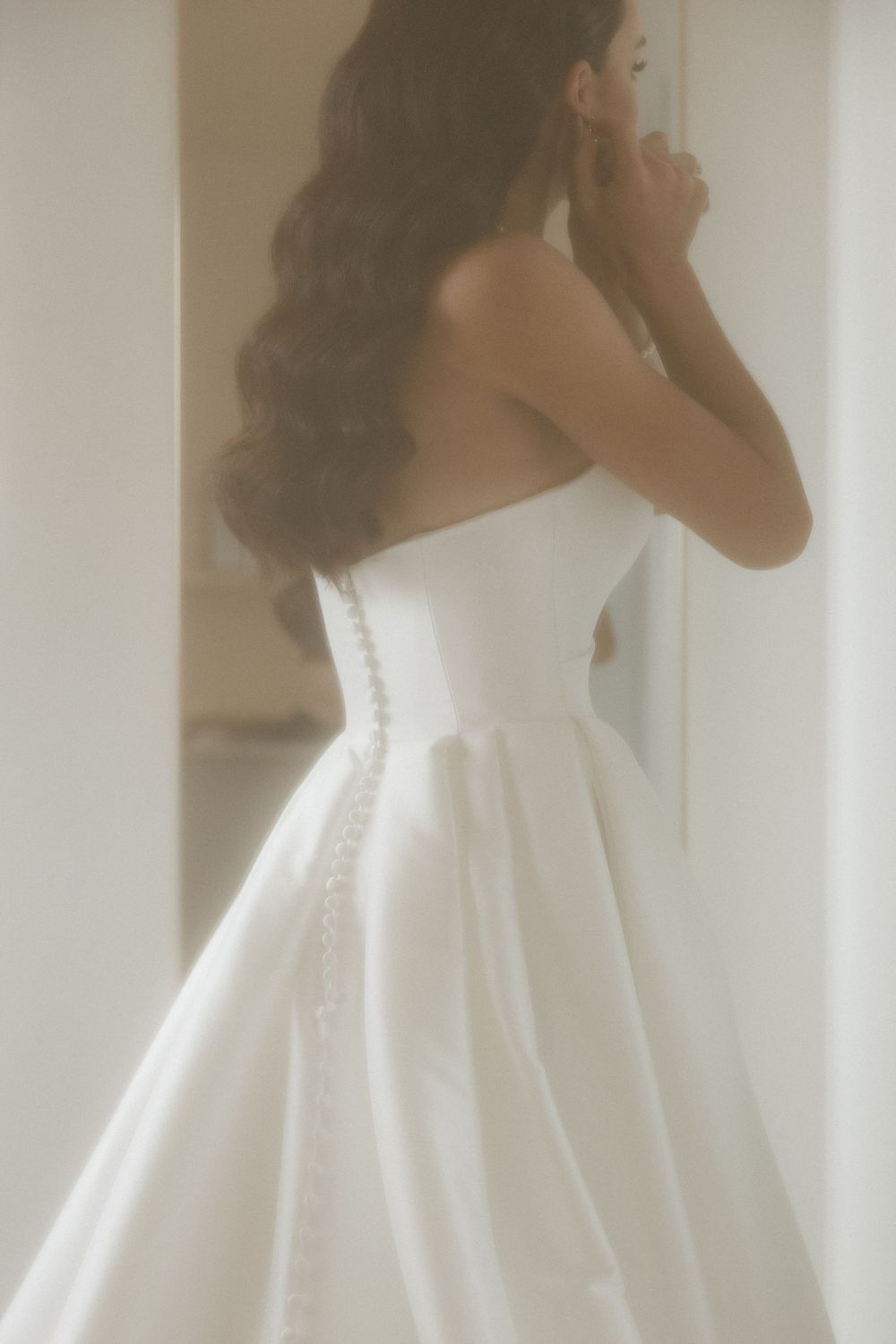 Close-up sequence of a bride in a white wedding dress with button details along the back.