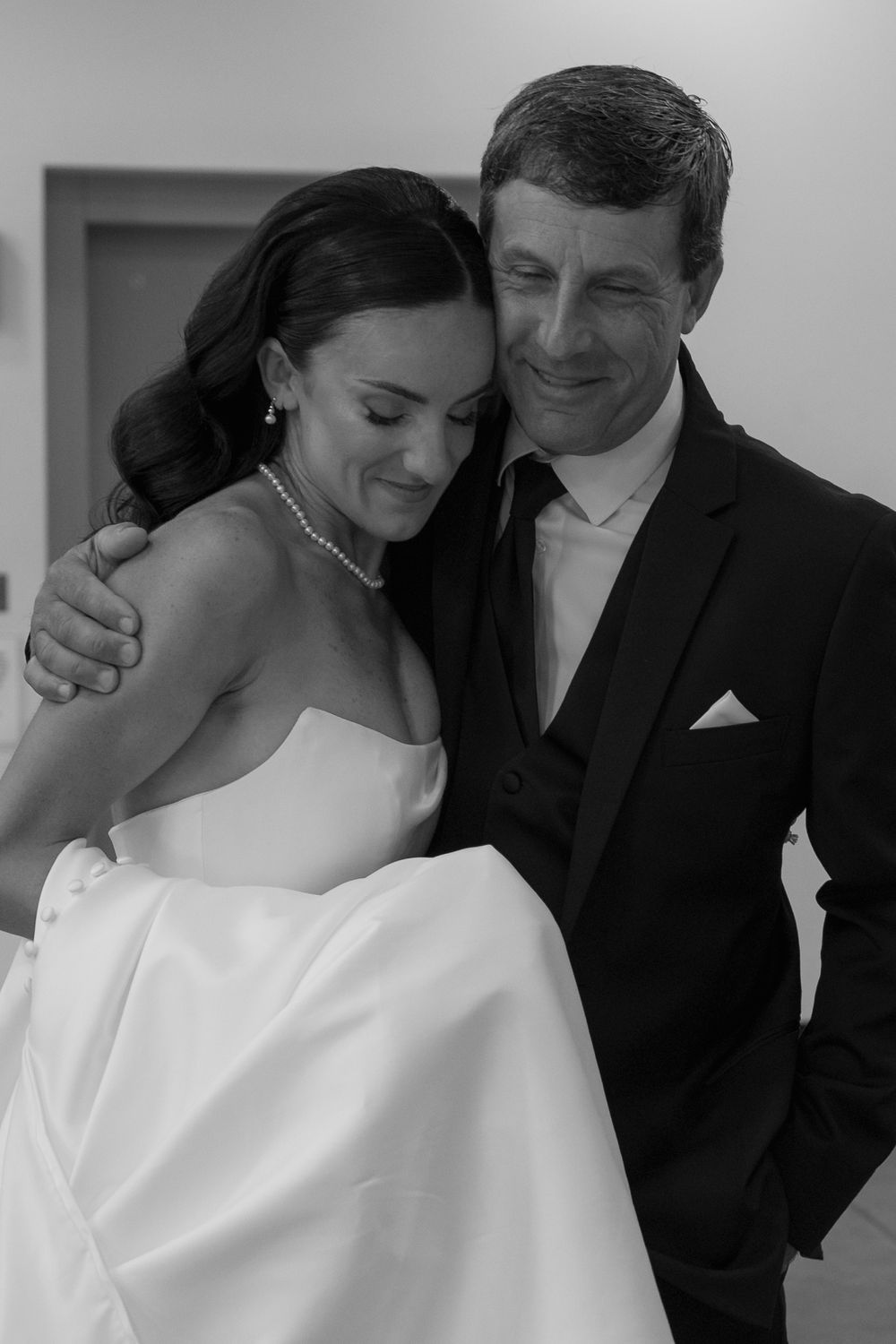 Intimate black and white portrait of couple embracing in formal wedding attire.
