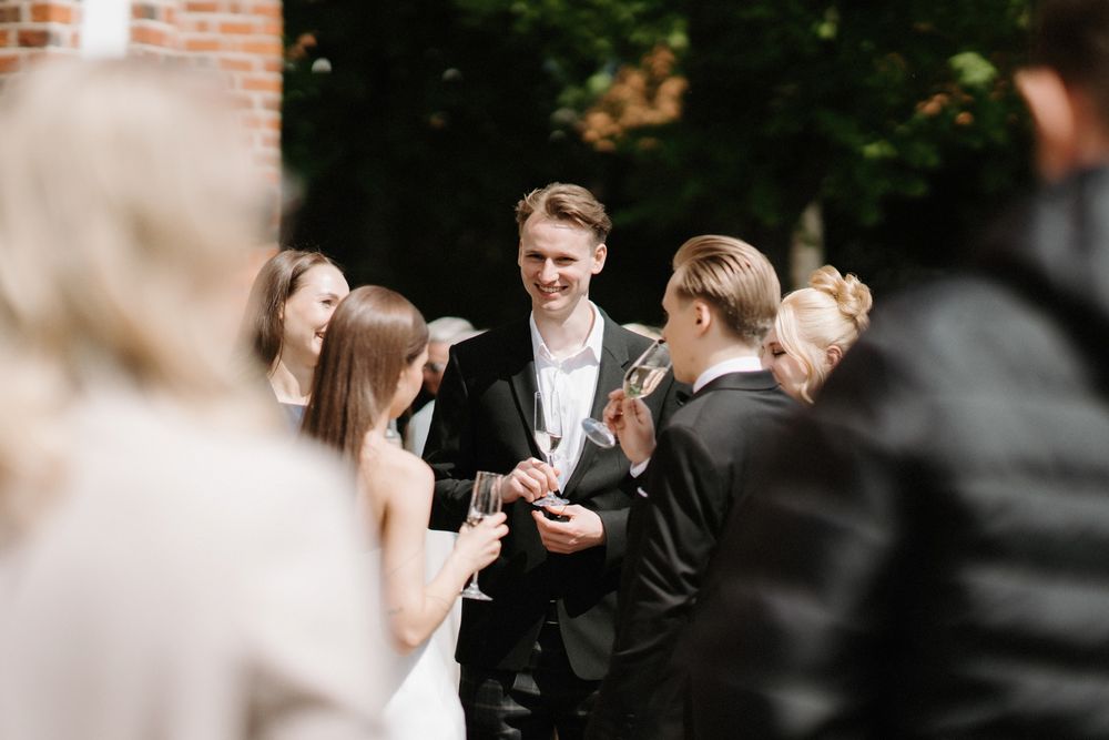 Wedding guests gathered outdoors in formal attire mingling at a social event.