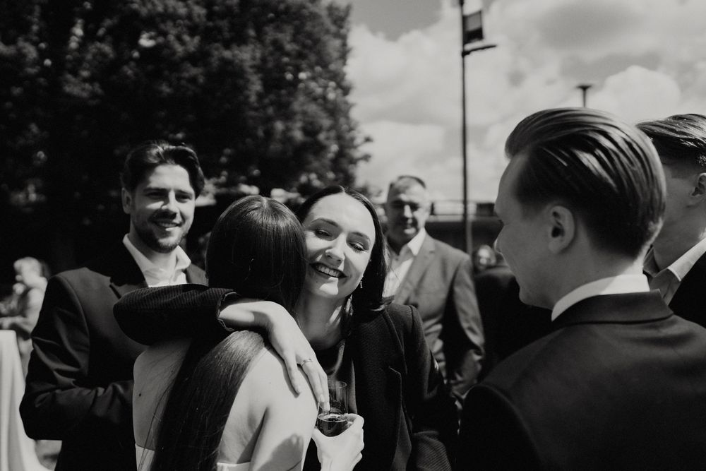 Black and white photo of wedding guests socializing at an outdoor reception.
