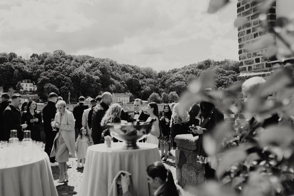 Wedding reception setup with tables and guests against brick architecture.