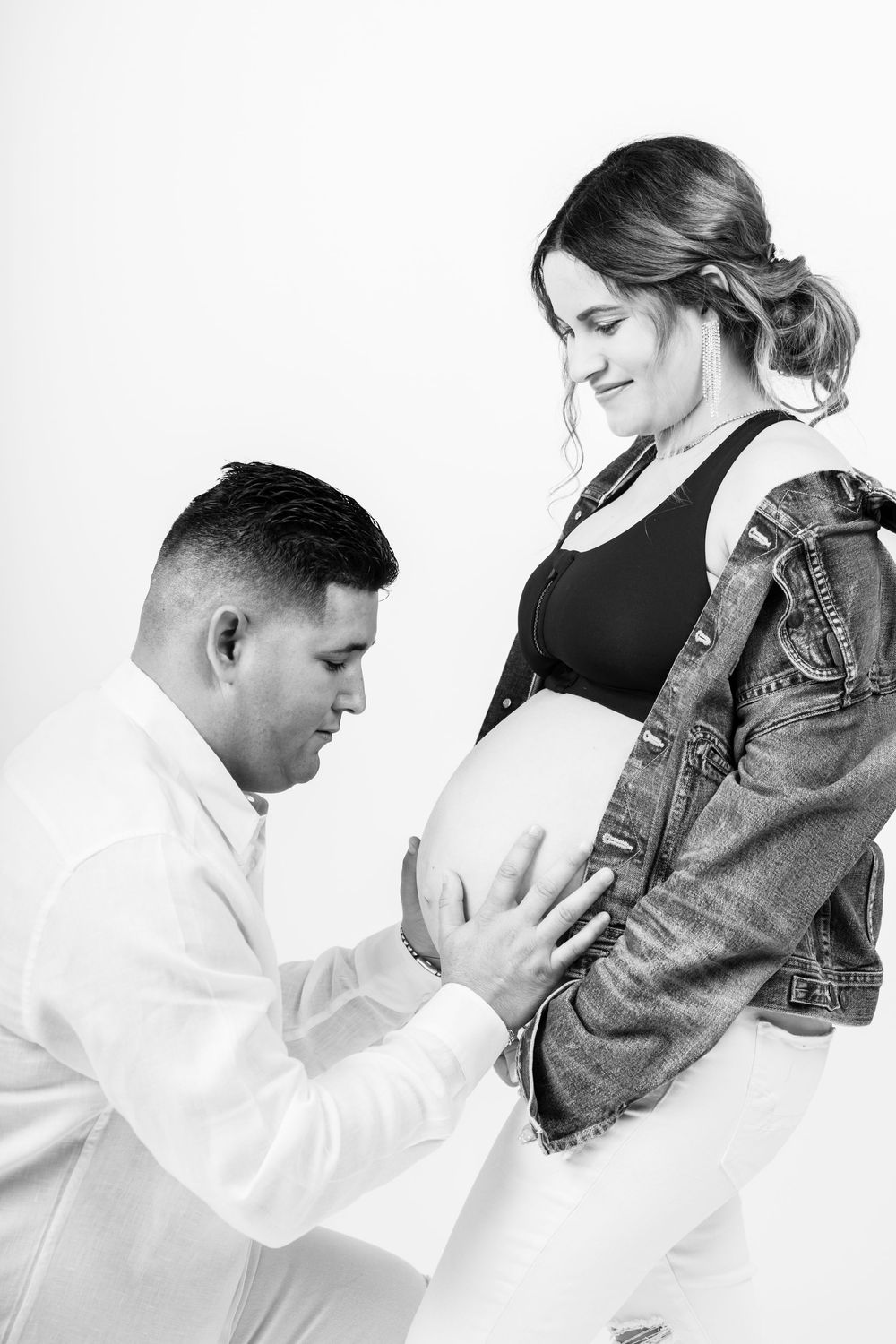 Black and white maternity photos showing tender moments between expecting couple.