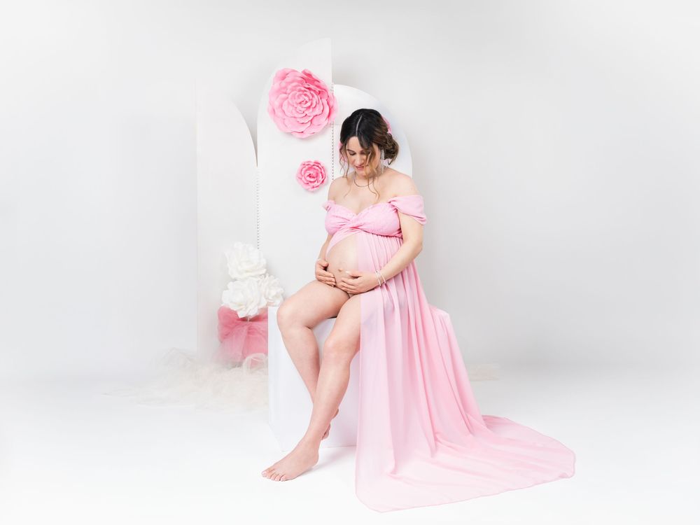 Elegant maternity portraits featuring pink flowy dress and romantic styling.