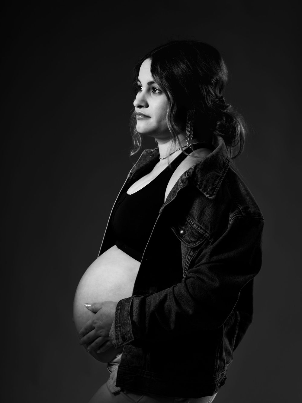 Dramatic black and white maternity portraits showing silhouette in dark lighting.