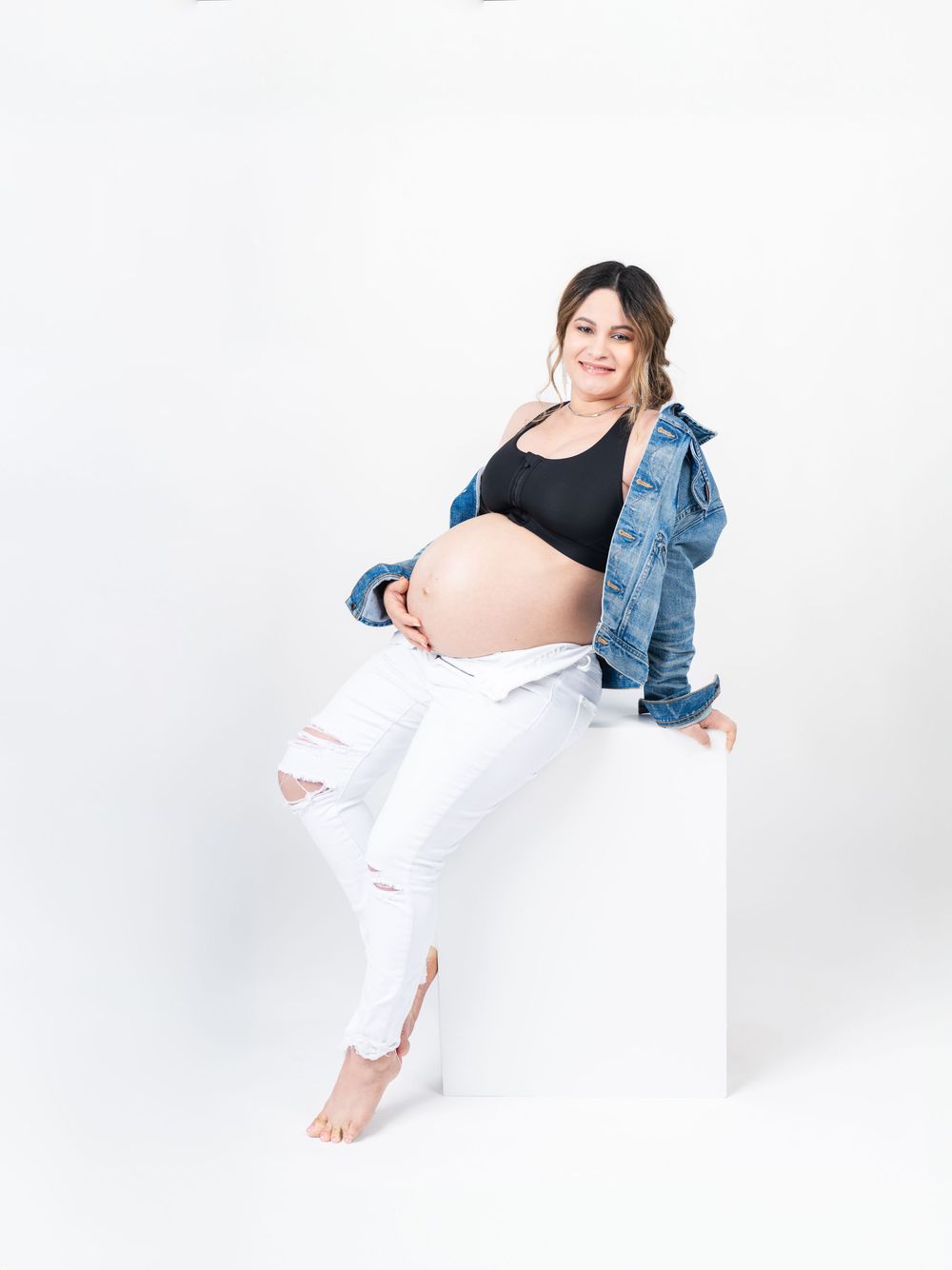 Modern maternity portraits with denim jacket and distressed white pants.