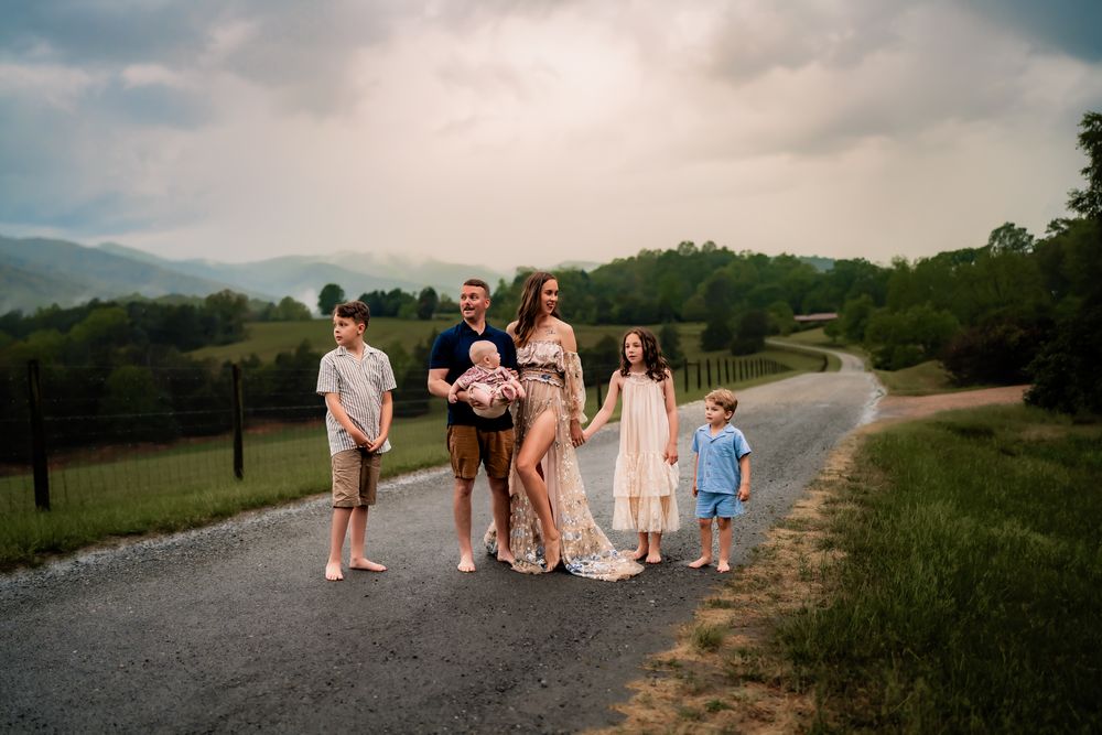 Group of people gathered on a scenic mountain road at sunset for a casual outdoor gathering.
