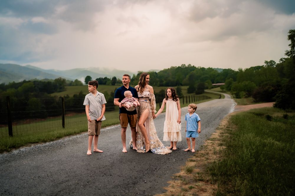 A family group gathers for a casual moment together on a winding mountain path under cloudy skies.