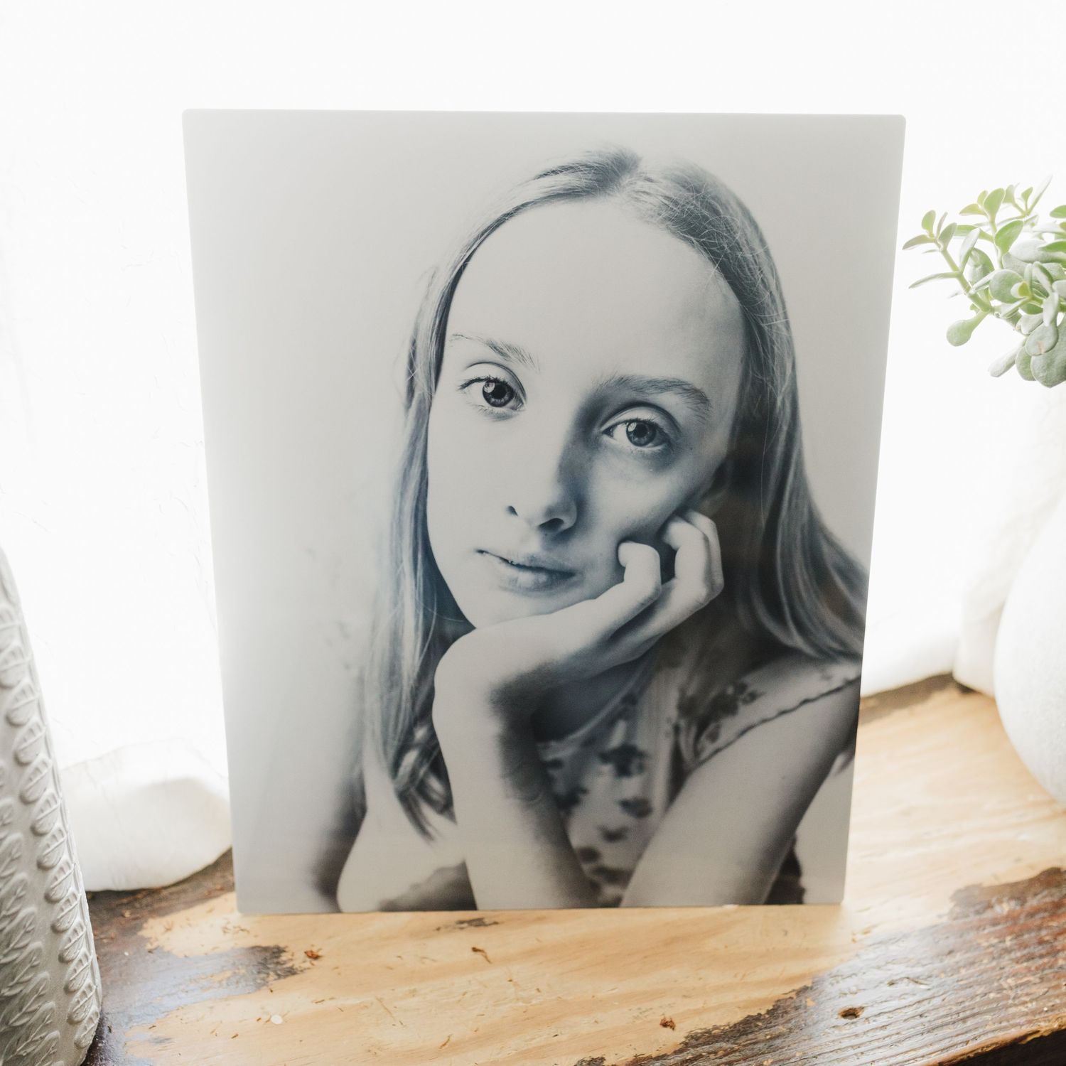 Black and white portrait drawing resting against wall near plants.