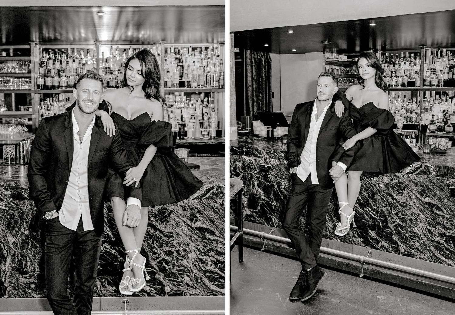 A black and white photograph of two people posing playfully at a bar with bottles displayed in the background.