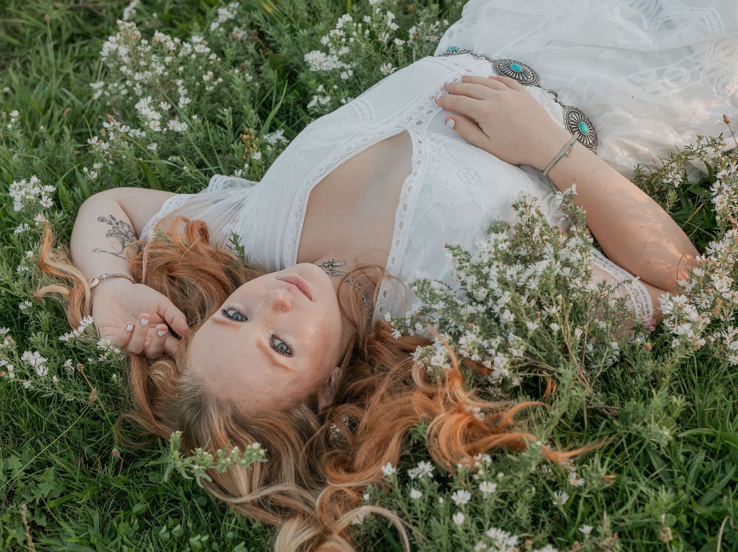 High School Senior girl posing in a field of white flowers for her senior portraits.