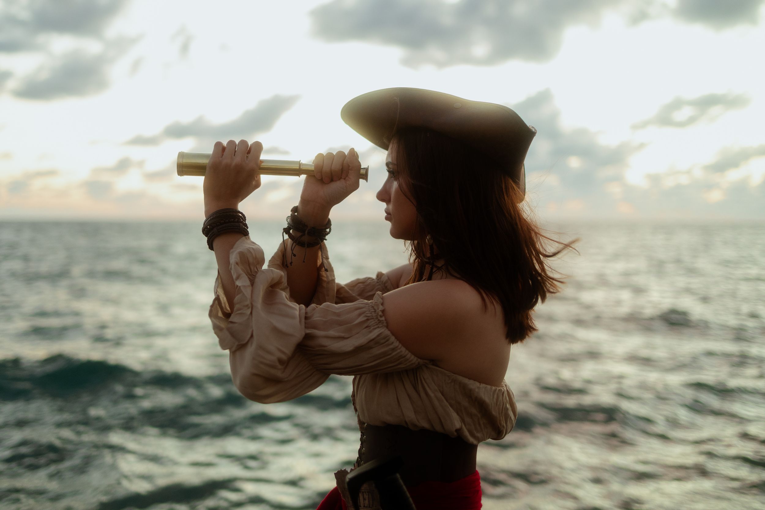 Silhouette of pirate woman raising arms by the ocean, Jack Sparrow inspired cosplay. Ft Lauderdale editorial shoot by Mannyportraits.