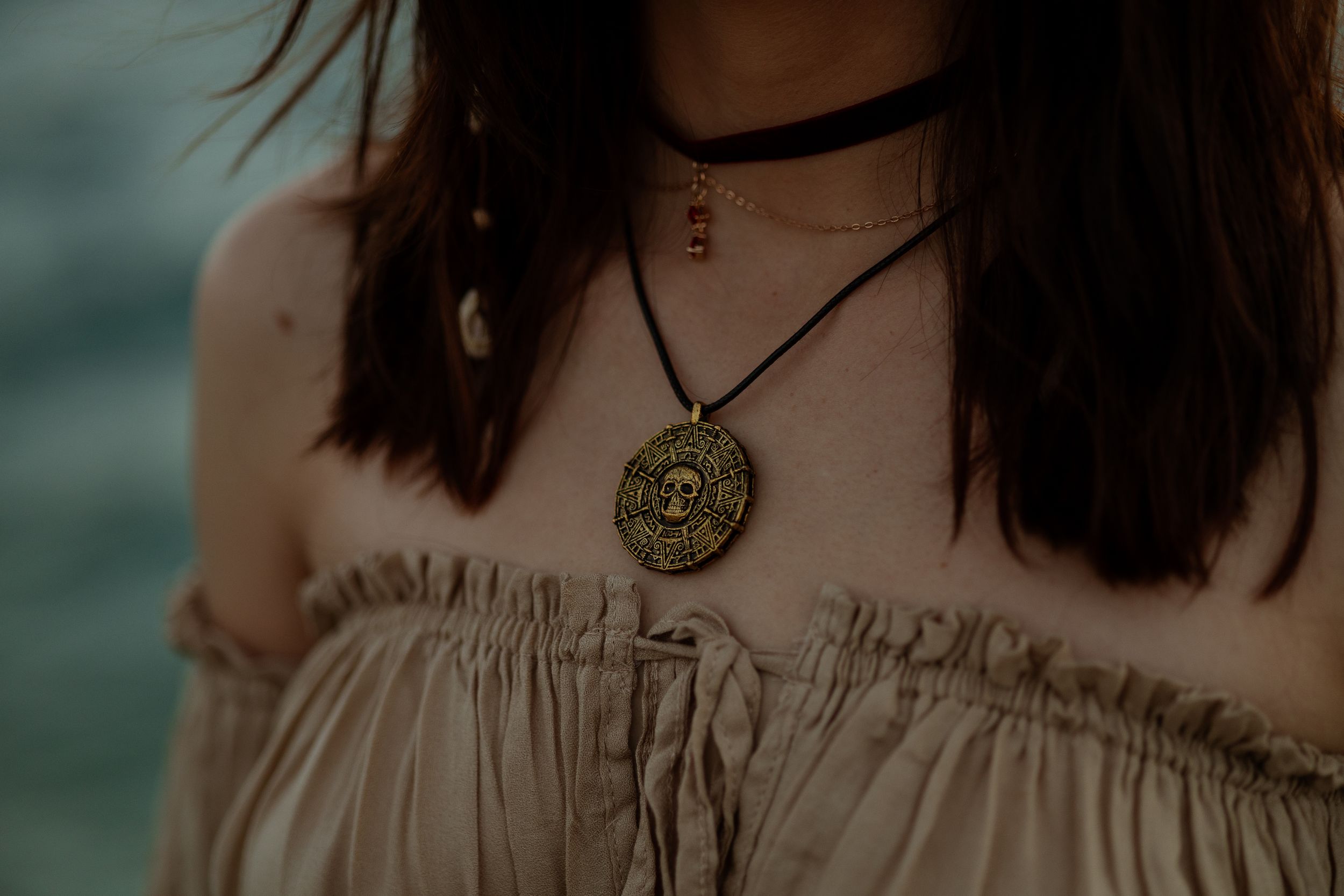 Close-up of pirate medallion necklace on model’s chest, styled for actors & performers. Miami cinematic portrait photography.