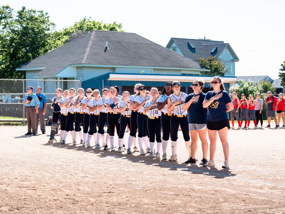 Baseball team players lined up on dusty field during game ceremony or opening day event.