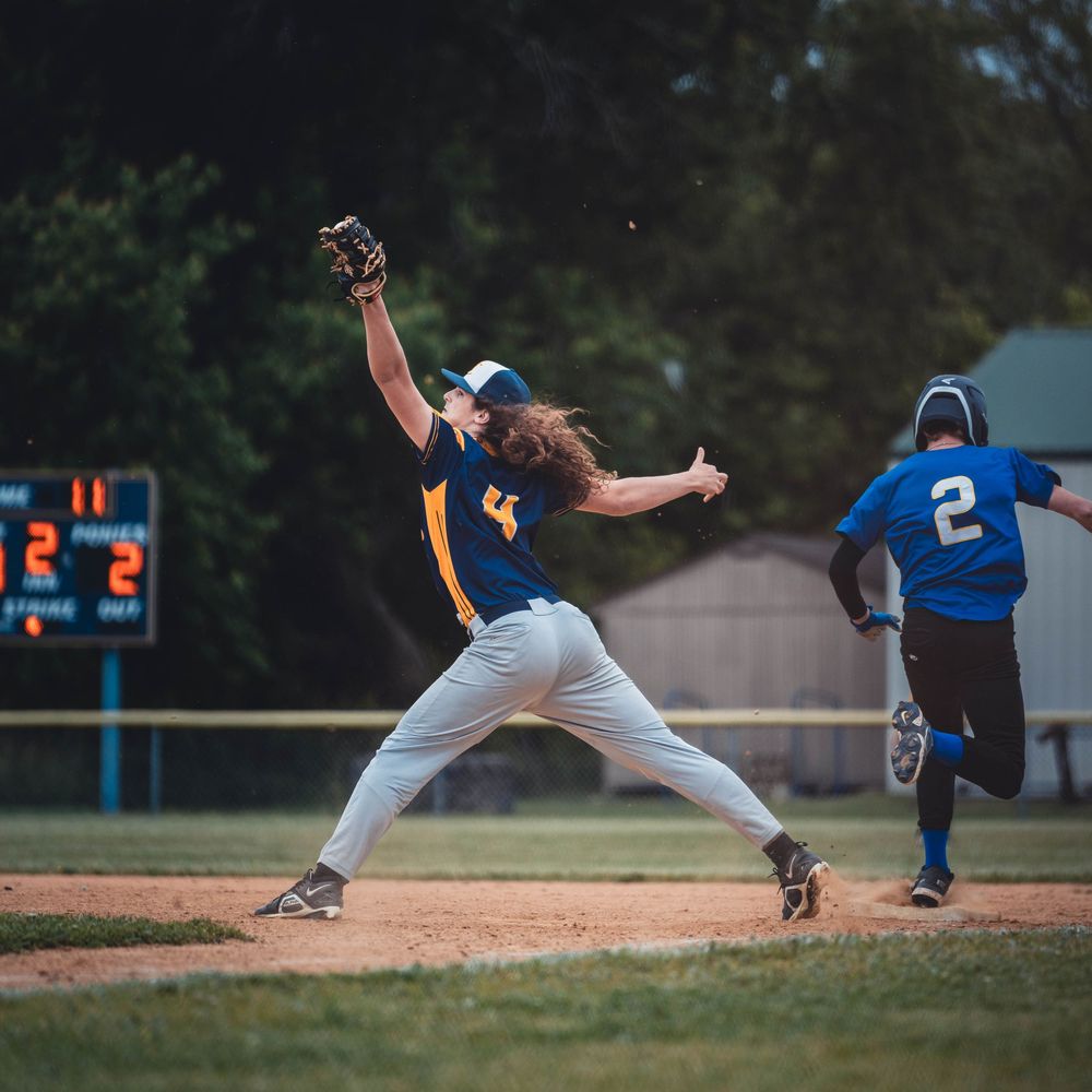 A baseball fielder makes a spectacular diving catch attempt on the field during a game, diving sideways into the air.