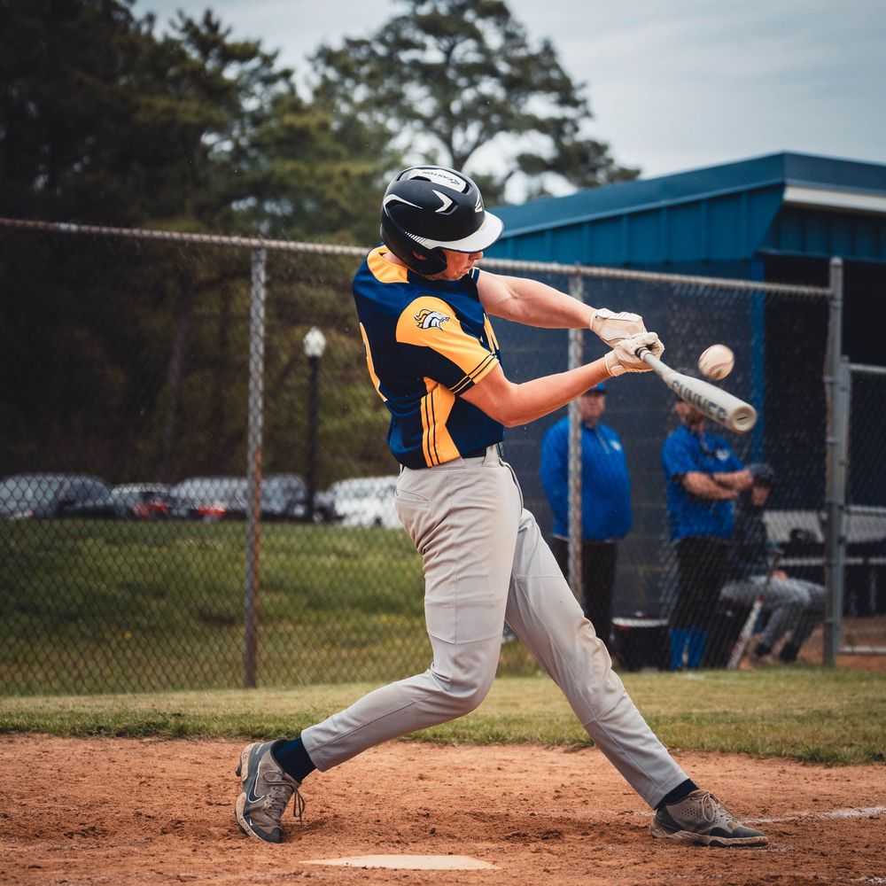 Baseball batter at the plate focusing on contact while swinging at an incoming pitch during a game.