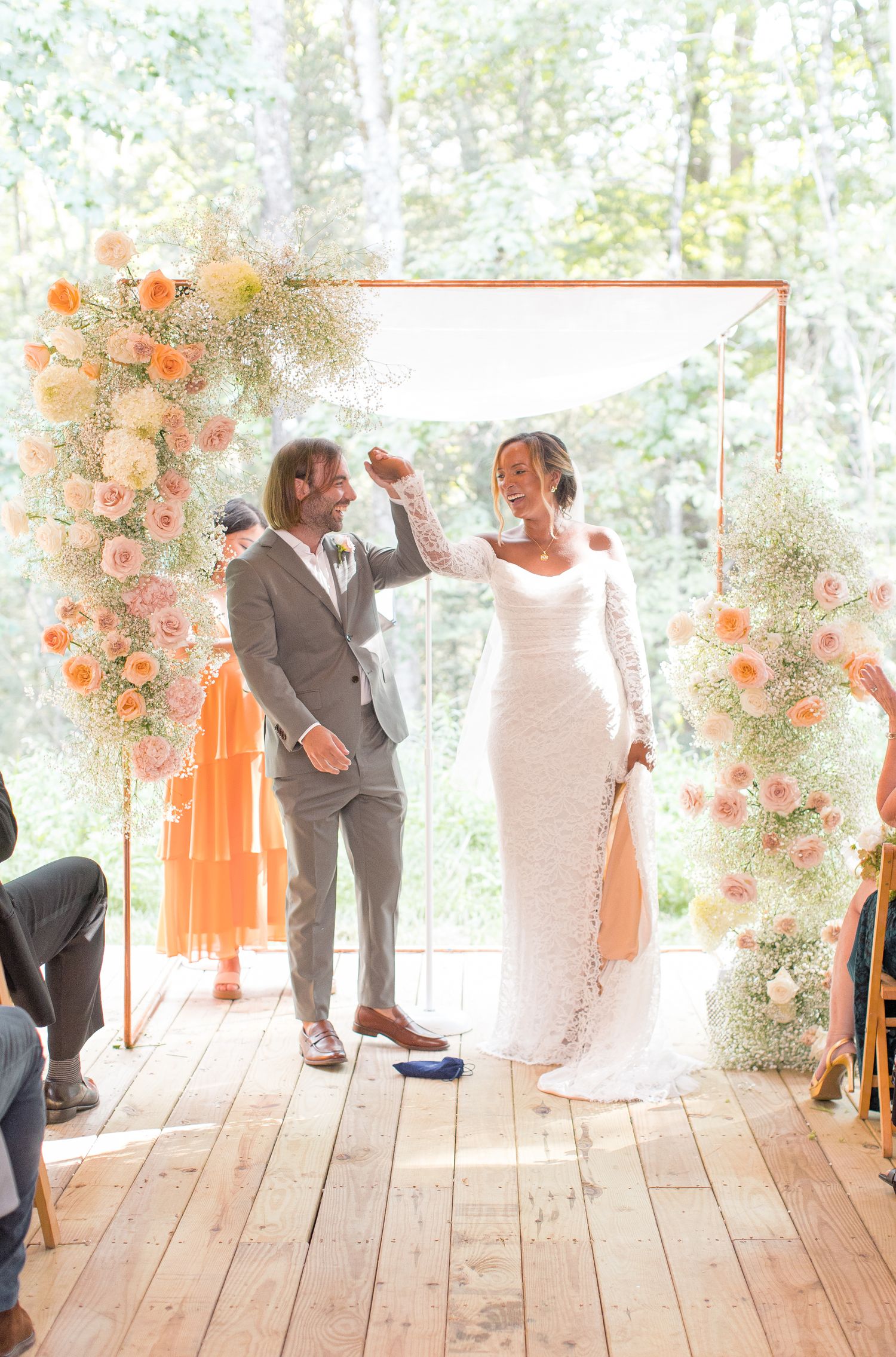 Wedding couple shares playful dancing moments across multiple photos on rustic wooden deck with peach floral decor.