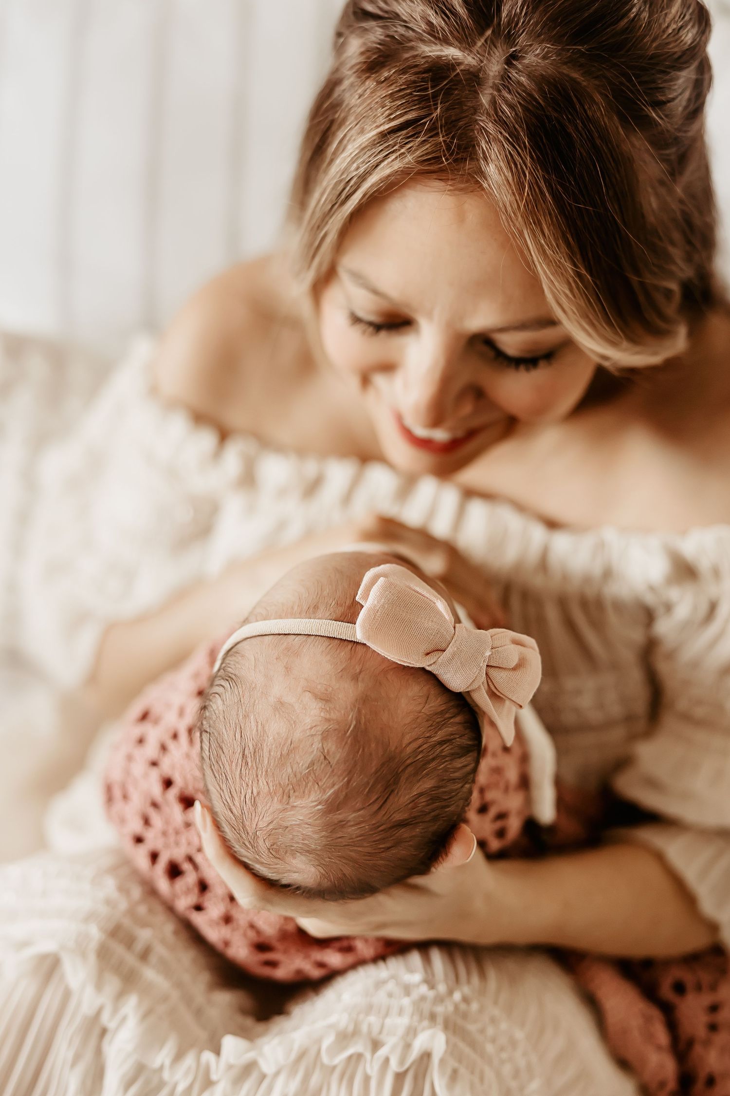 A mother gazes down at her baby girl while an Oahu newborn photographer focuses on the details of her newborn hair on her head.
