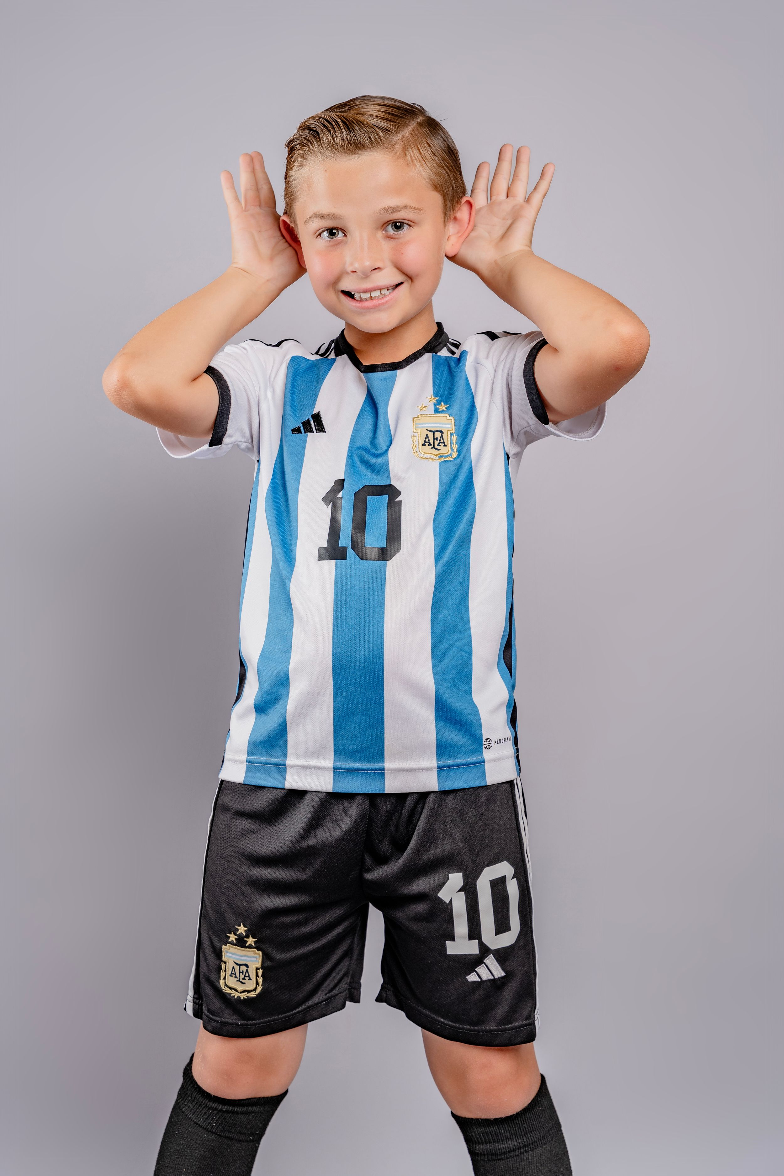 Young sports fan wears blue and white striped Argentina national team jersey with number 10 in various playful poses.