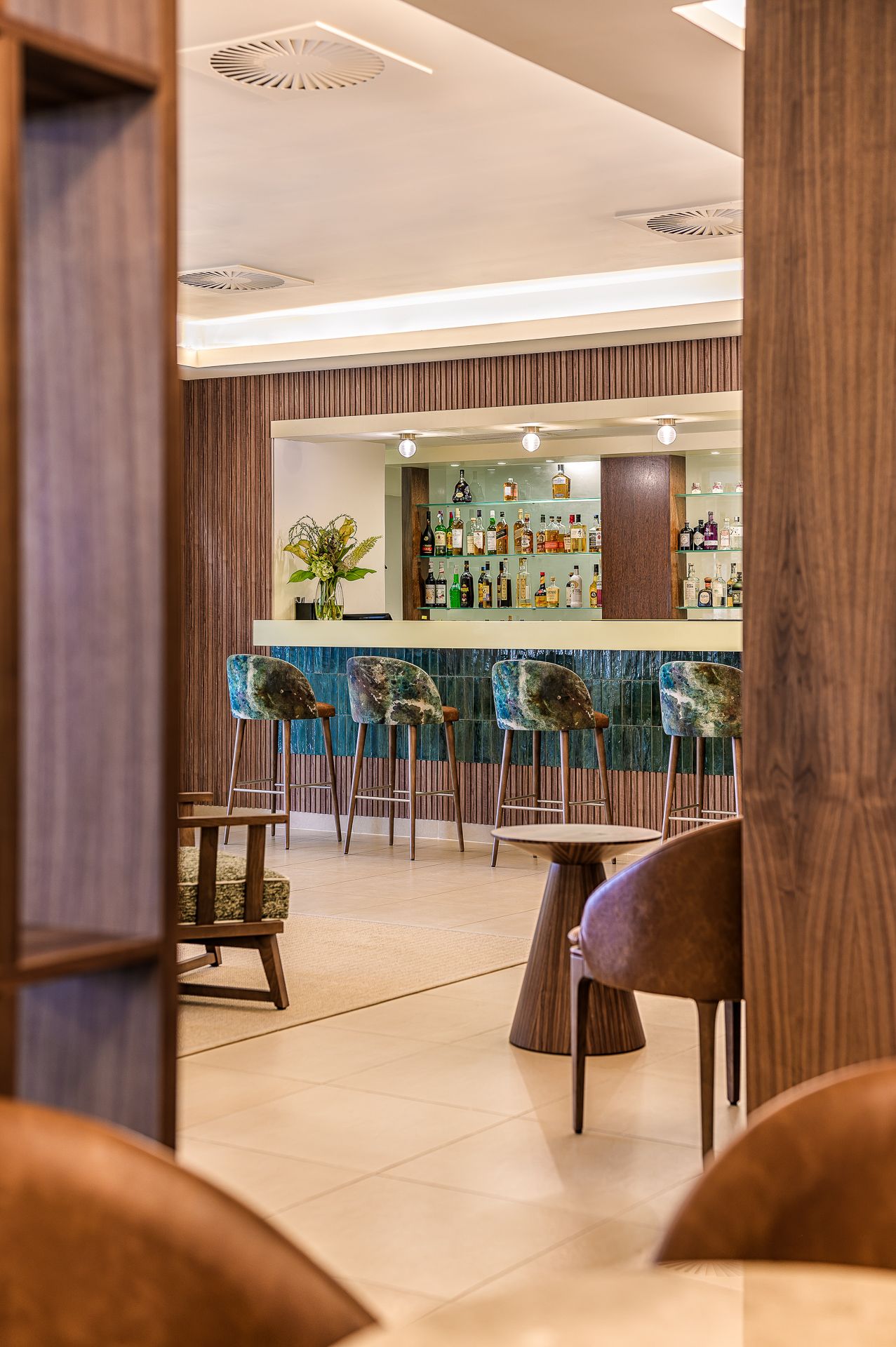 Modern hotel bar interior with wooden pillars, sleek bar counter, and contemporary seating in a minimalist design in the Algarve, by Paralle