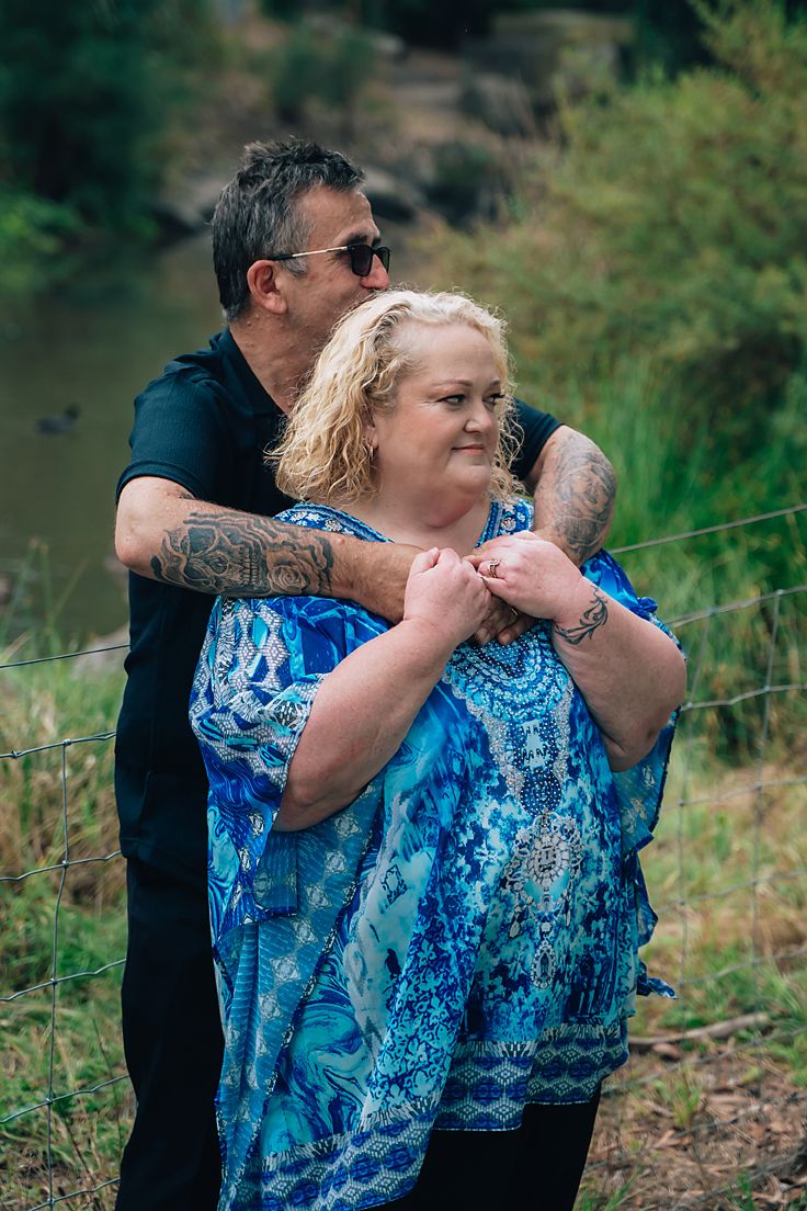 Person in a blue patterned dress stands outdoors by a lake or pond, appearing to be blowing something in a series of photos.
