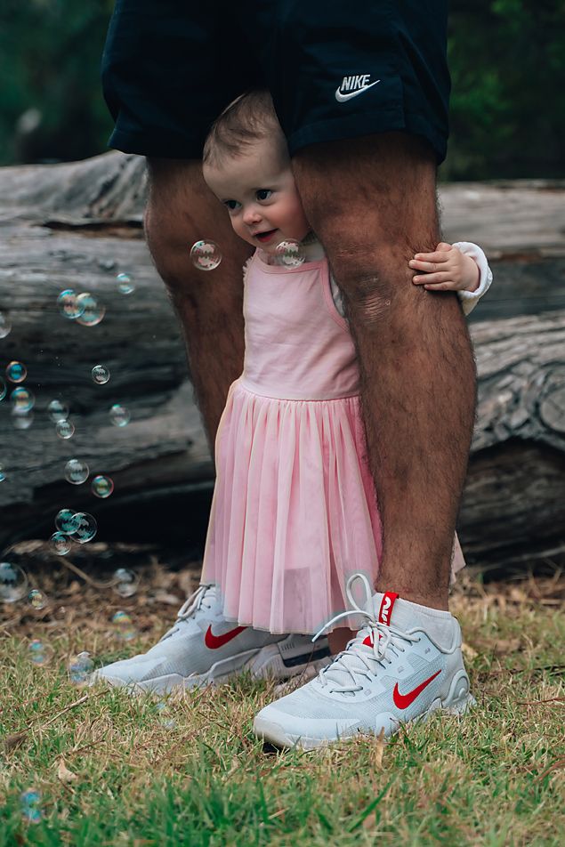 A pink dress and white Nike sneakers are shown in a sequence of progressive shots on grass near a fallen log.