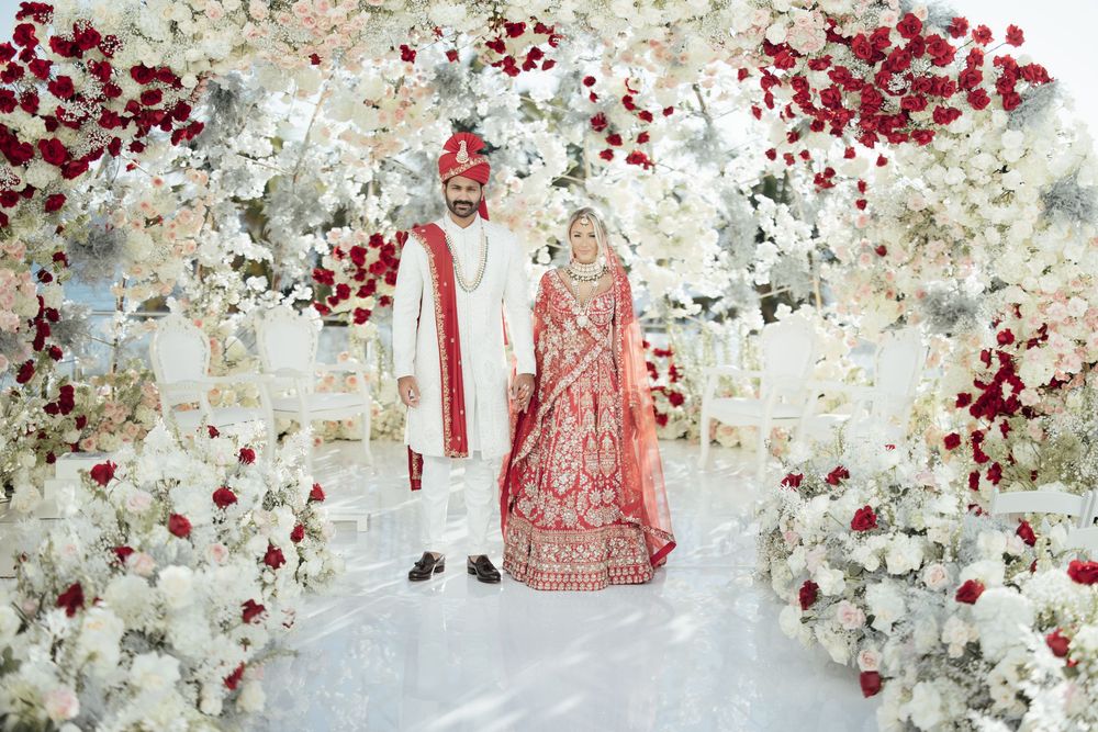 Traditional wedding ceremony decor featuring delicate red florals and elegant white embellishments along a wall.
