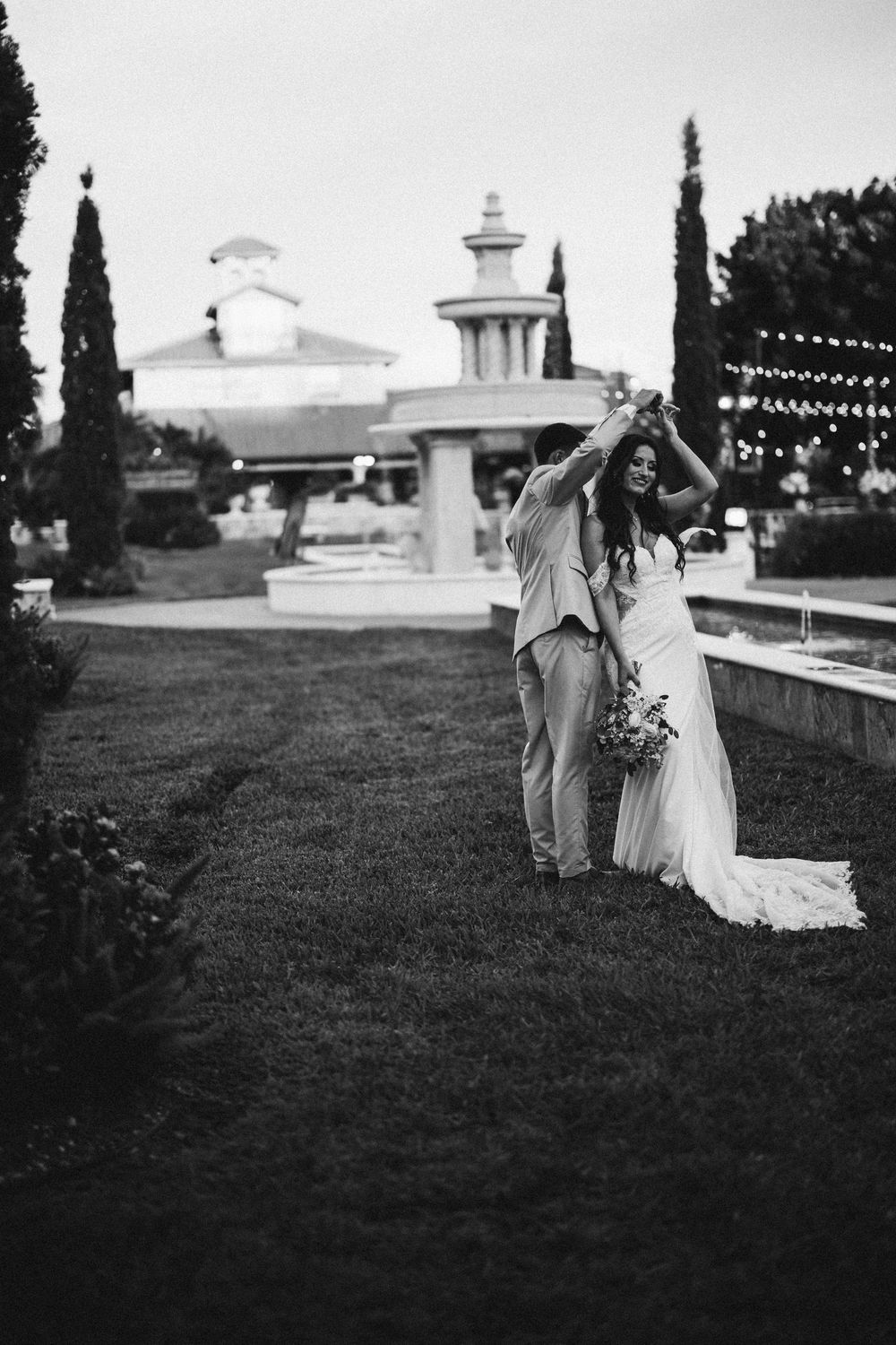 Black and white wedding photos showing romantic moments on a grassy hillside at sunset with white building in background.