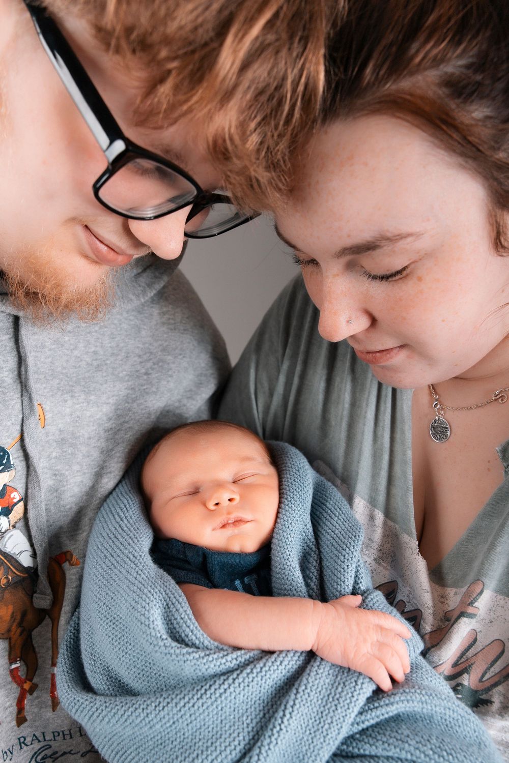 Intimate close-up sequence of parent bonding with newborn baby wearing soft blue clothing.