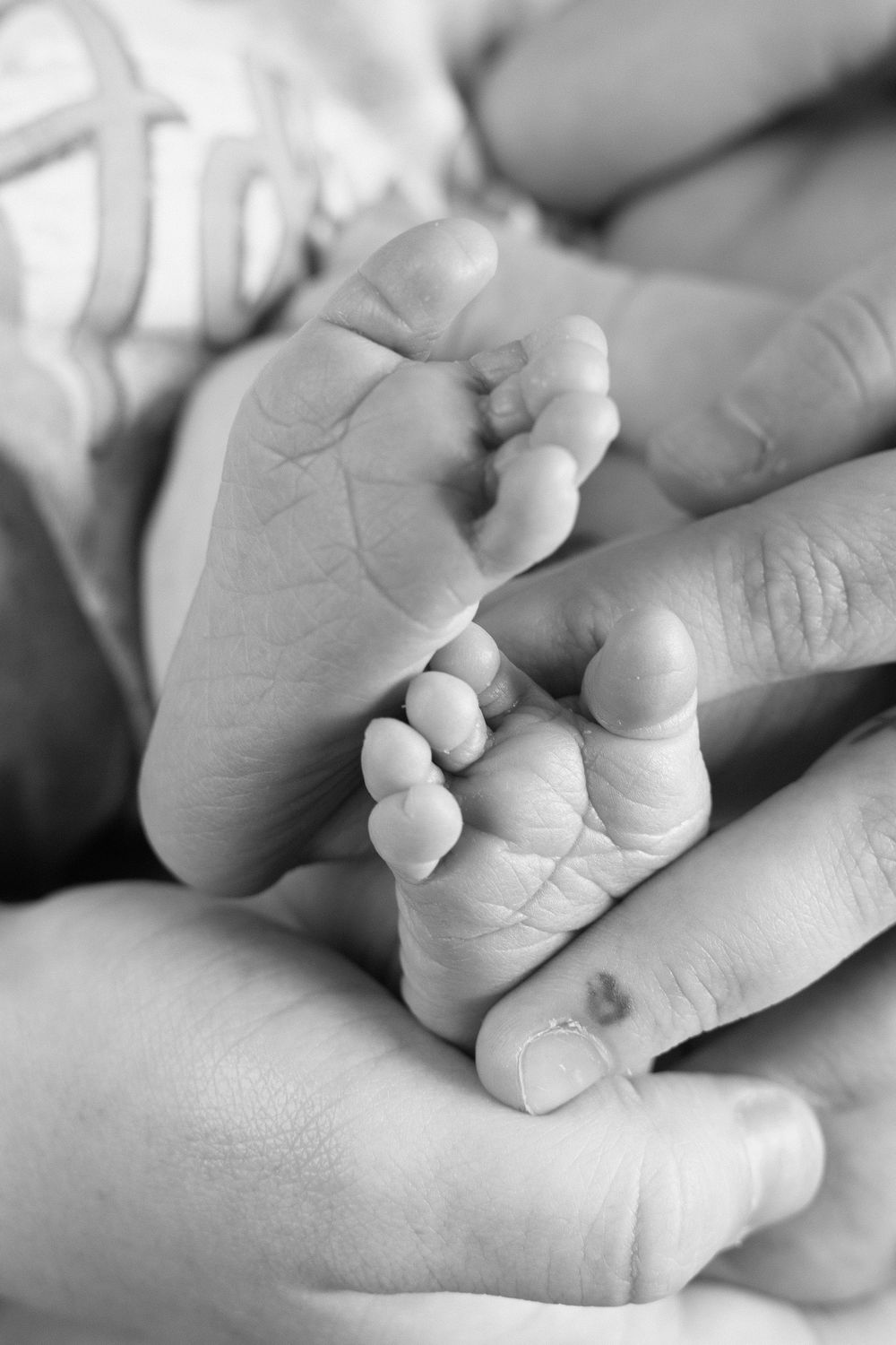 Black and white macro shots of tiny newborn baby fingers holding an adult's finger.